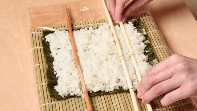 巻きすに海苔全型1枚を置き白の酢飯を広げ、菜箸で手前側に2本、向こう側に1本へこみをつける